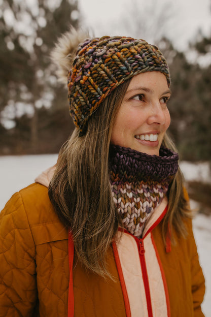 Woman wearing a colorful brown knitted hat and scarf in a snowy outdoor setting