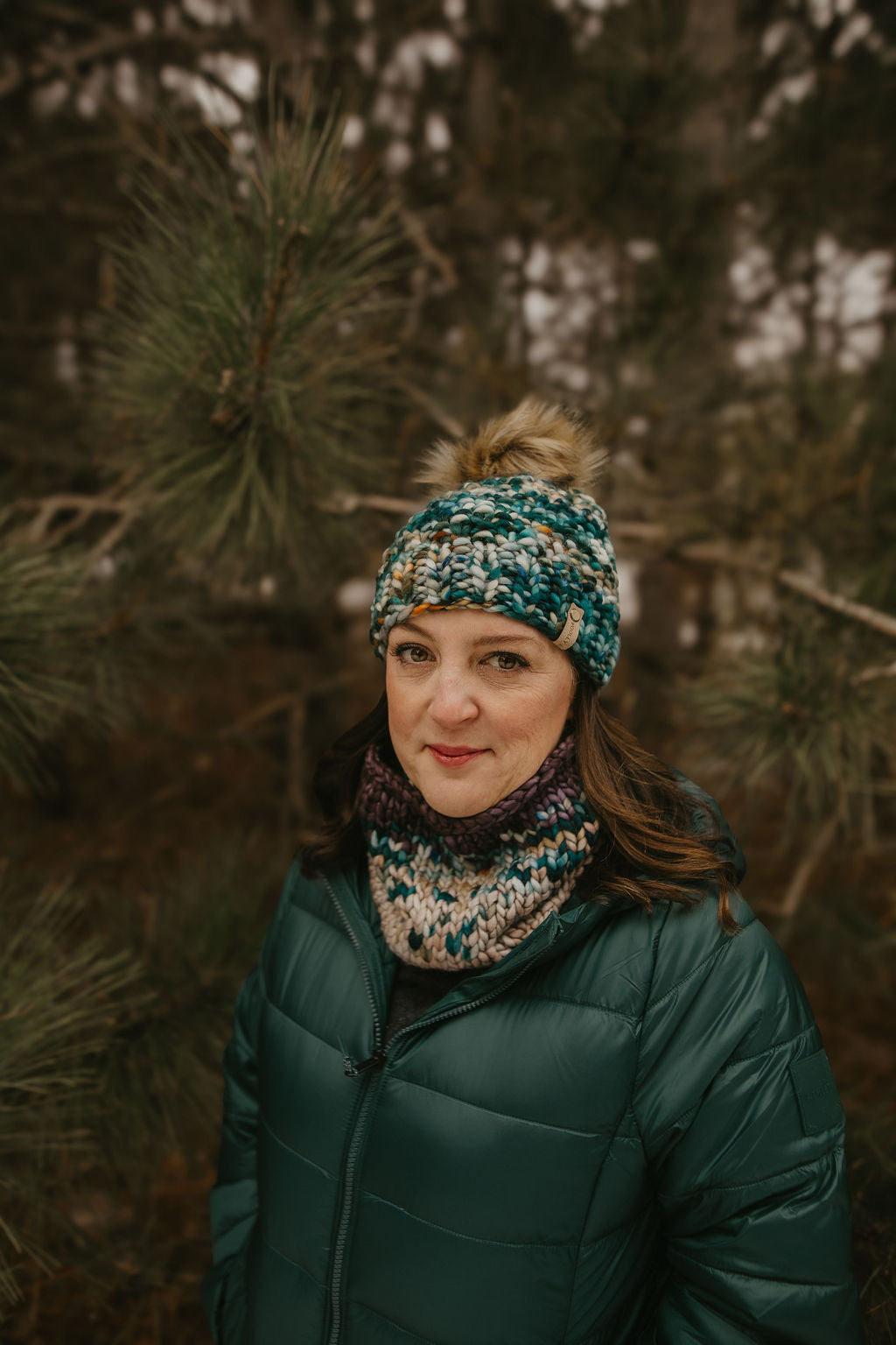 Woman wearing a green jacket and colorful green merino wool hat in a forest setting
