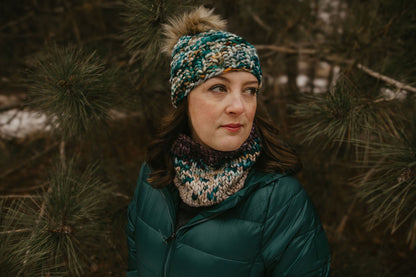 Woman wearing a textured green colorful knit hat and scarf in a forest setting