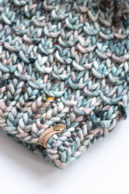 Close view of blue knitted hat and suede brand tag