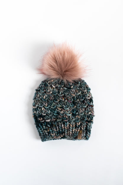 Dark blue knitted beanie with a pink pom-pom on a white background
