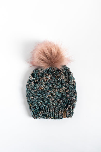 Dark blue knitted beanie with a fluffy pink pom-pom on a white background