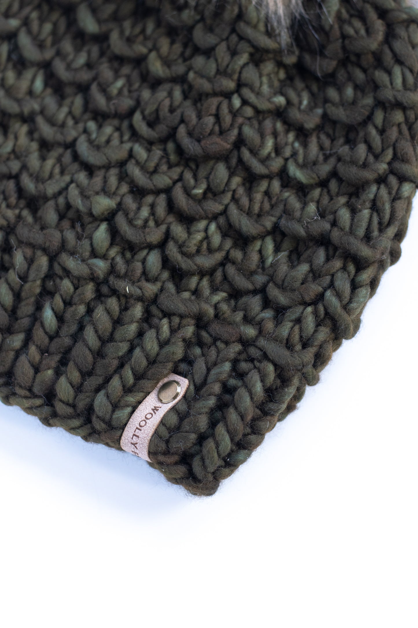 Green knitted hat with a brand tag on a white background
