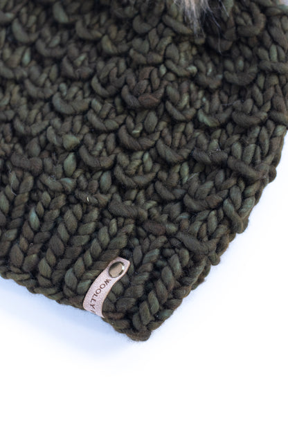 Green knitted hat with a brand tag on a white background