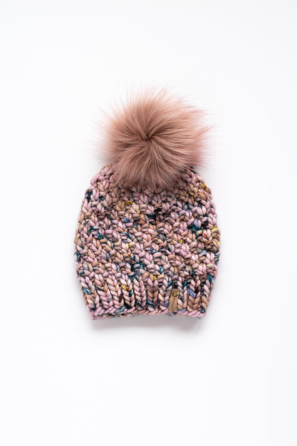 Pink knitted beanie with a pink pom-pom on a white background
