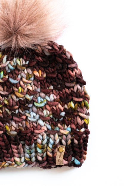 Multicolored knit beanie with a fluffy pom-pom on a white background