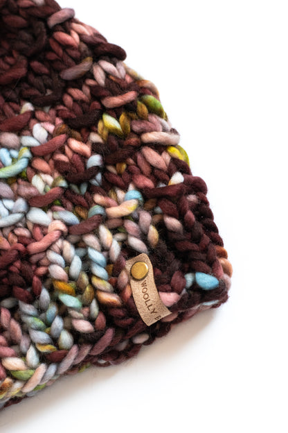 Close view of a multicolored knitted hat with a brand label on a white background