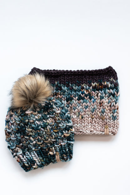 A green multicolor knit hat and a colorful knit cowl on a white background.