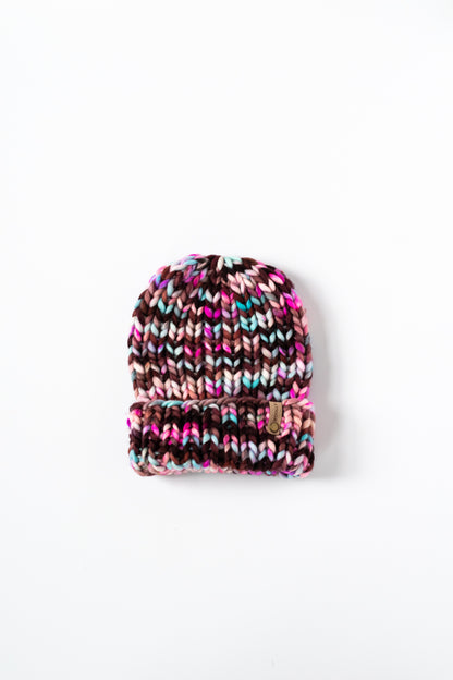 Pink and maroon multicolored knitted beanie on a white background