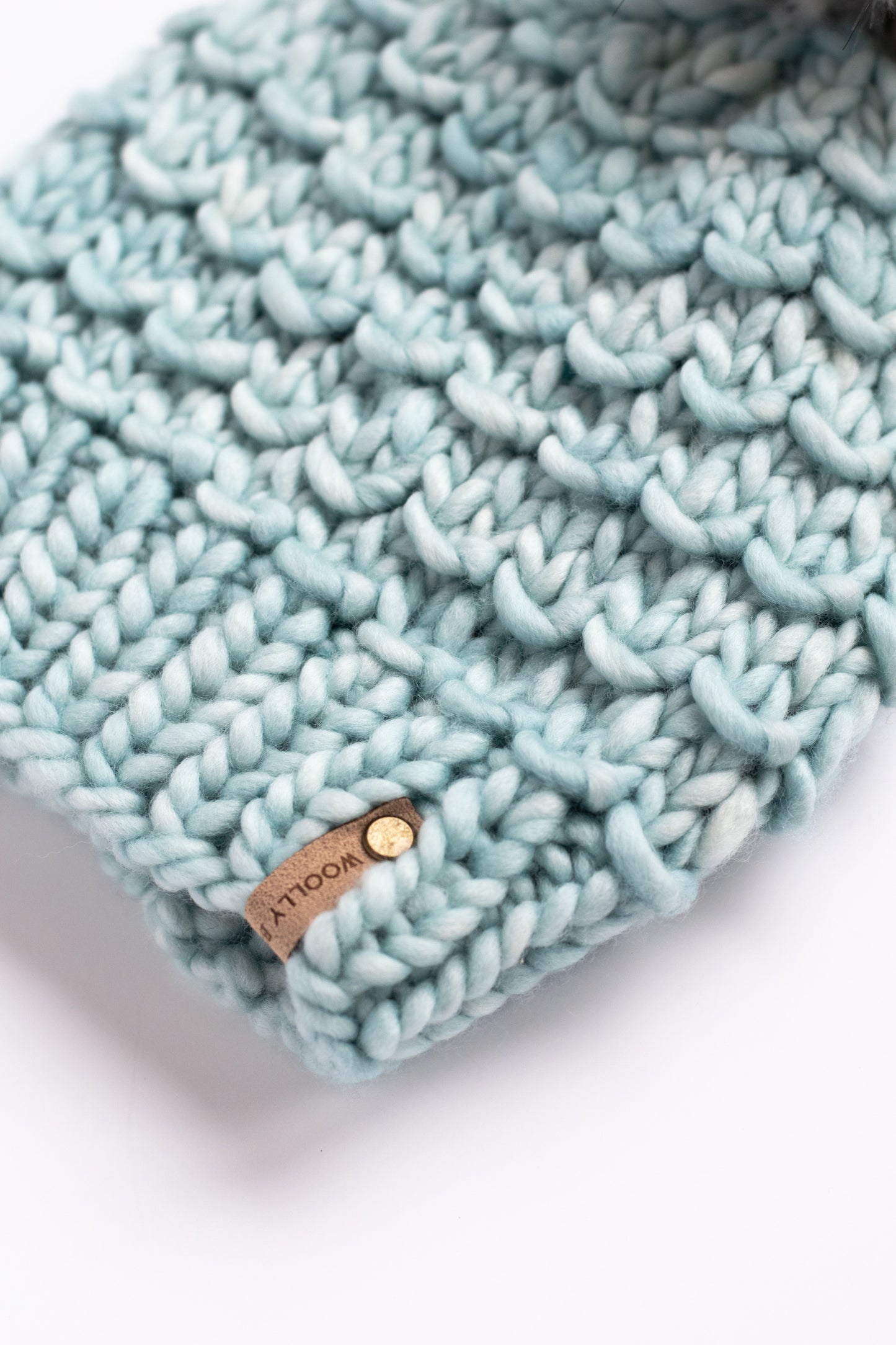 Light blue knitted headband with a brand label on a white background