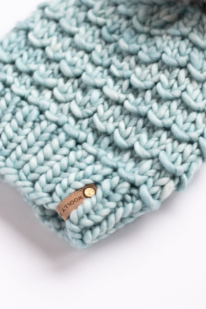 Light blue knitted headband with a brand label on a white background