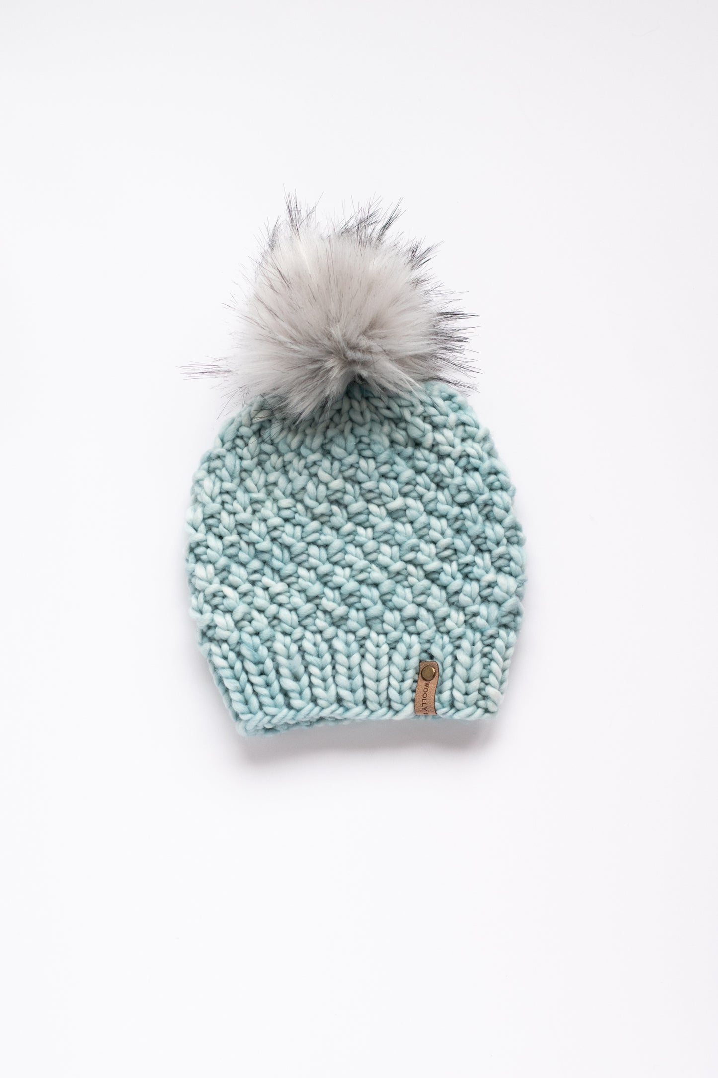 Light blue green knit beanie with a gray pom-pom on a white background