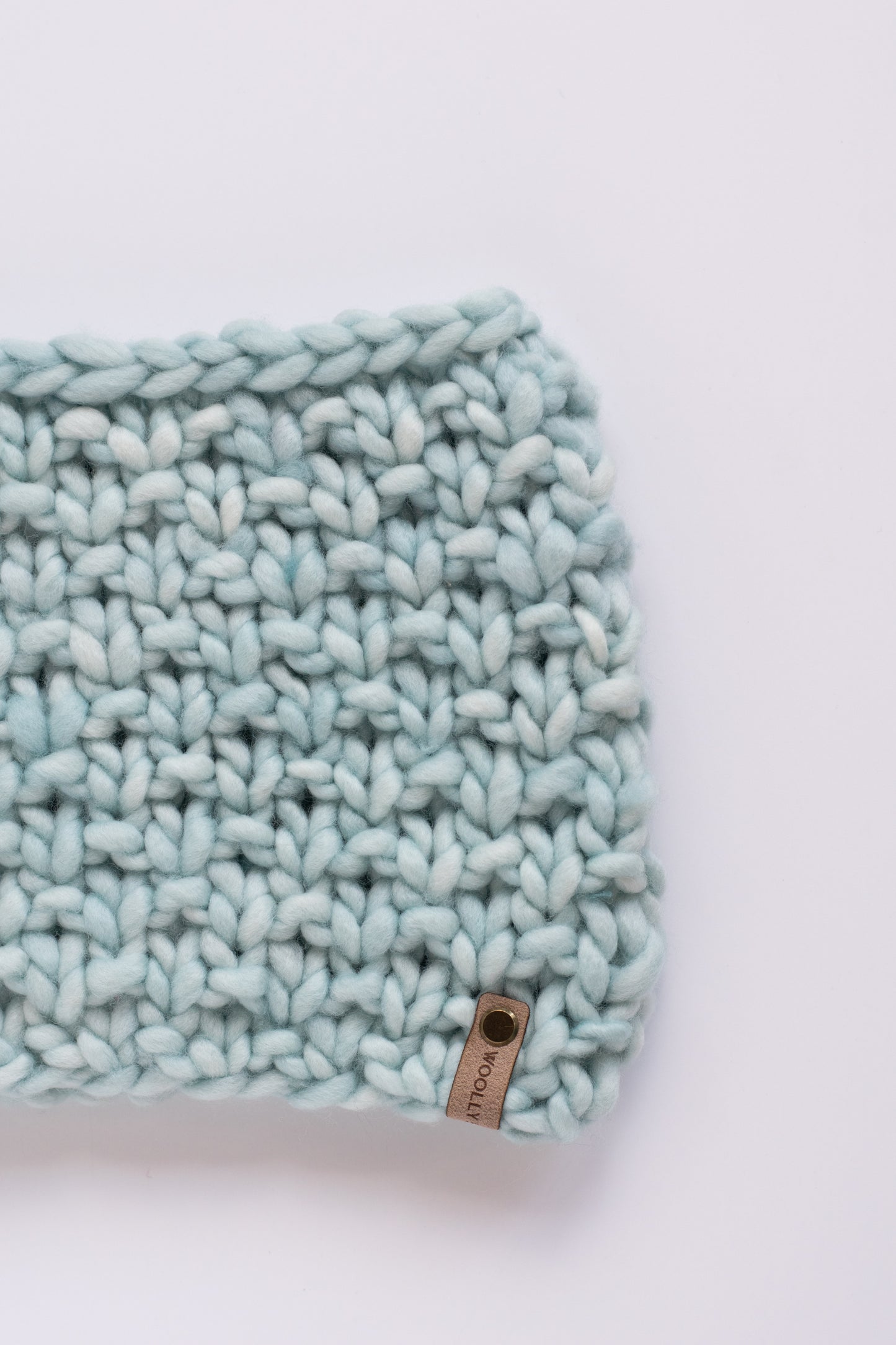Light blue textured scarf with a brand label on a white background