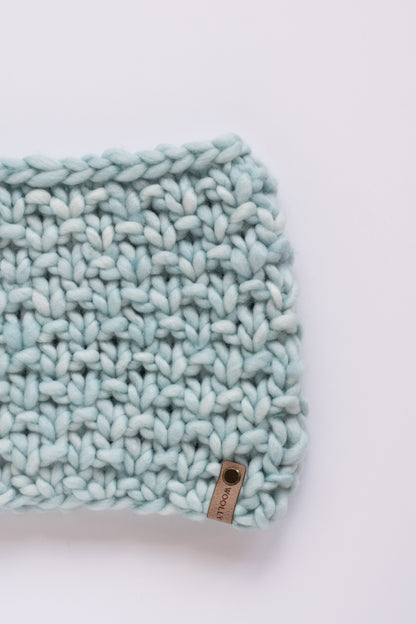 Light blue textured scarf with a brand label on a white background