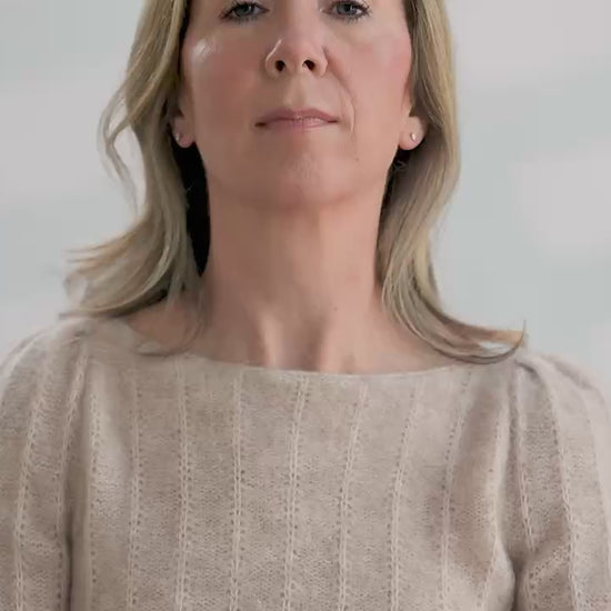 Woman tries on a colorful hand knit fair isle cowl in front of a white background