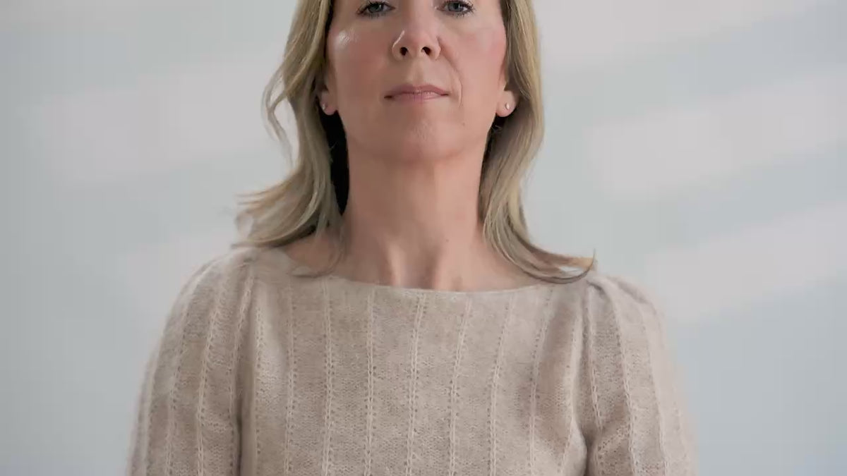 Woman tries on a colorful hand knit fair isle cowl in front of a white background