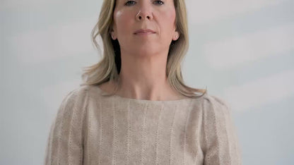 Woman tries on a colorful hand knit fair isle cowl in front of a white background