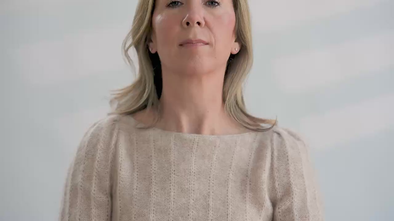 Woman tries on a colorful hand knit fair isle cowl in front of a white background