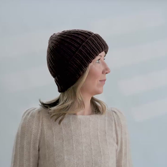 Woman tries on hand knit ribbed beanies in different colors