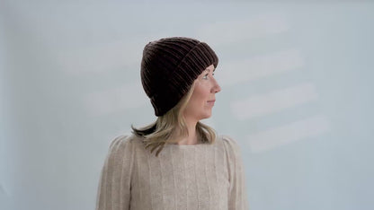 Woman tries on hand knit ribbed beanies in different colors