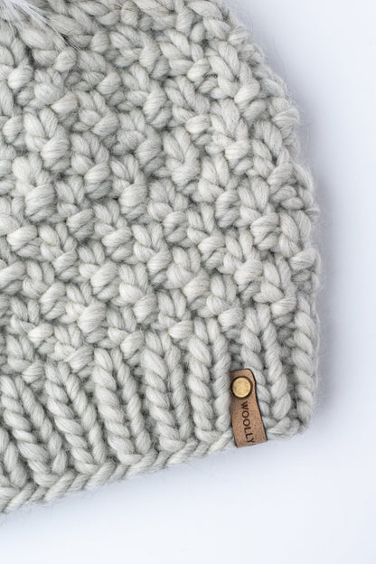 Close up of a light gray knitted hat on a white background