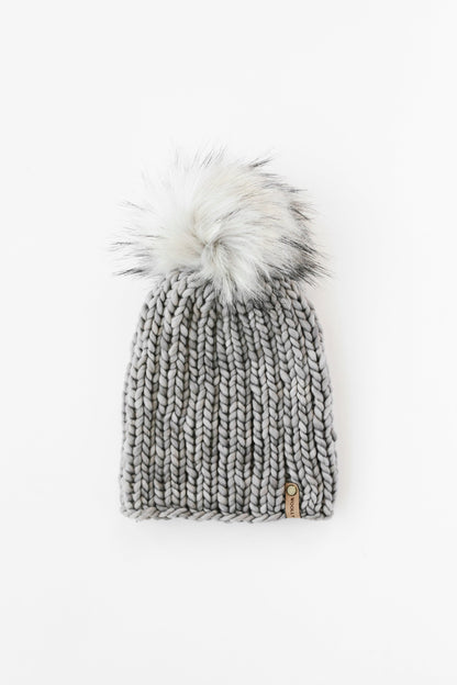 Gray chunky knit ribbed beanie with gray faux fur pom pom on white background